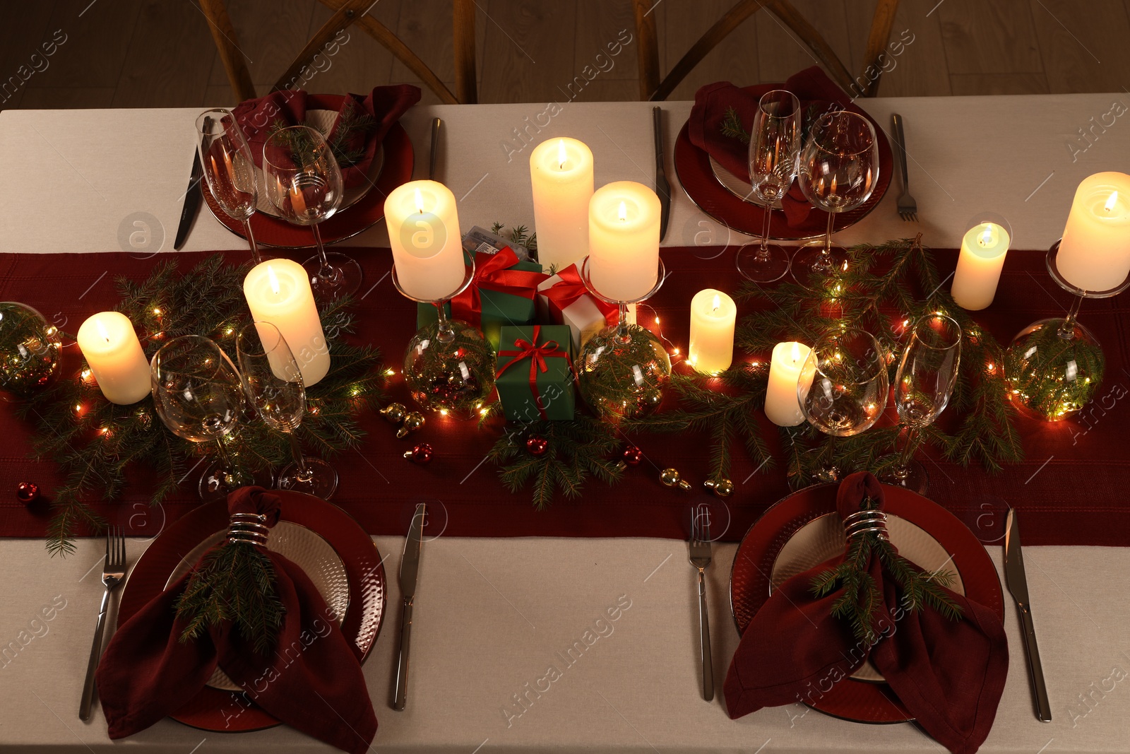 Photo of Christmas table setting with burning candles and festive decor, above view