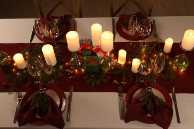 Christmas table setting with burning candles and festive decor, above view