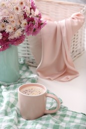 Photo of Cup of fresh coffee and beautiful bouquet on white table