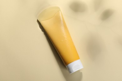 Photo of Tube of face cleansing product in water against beige background, top view