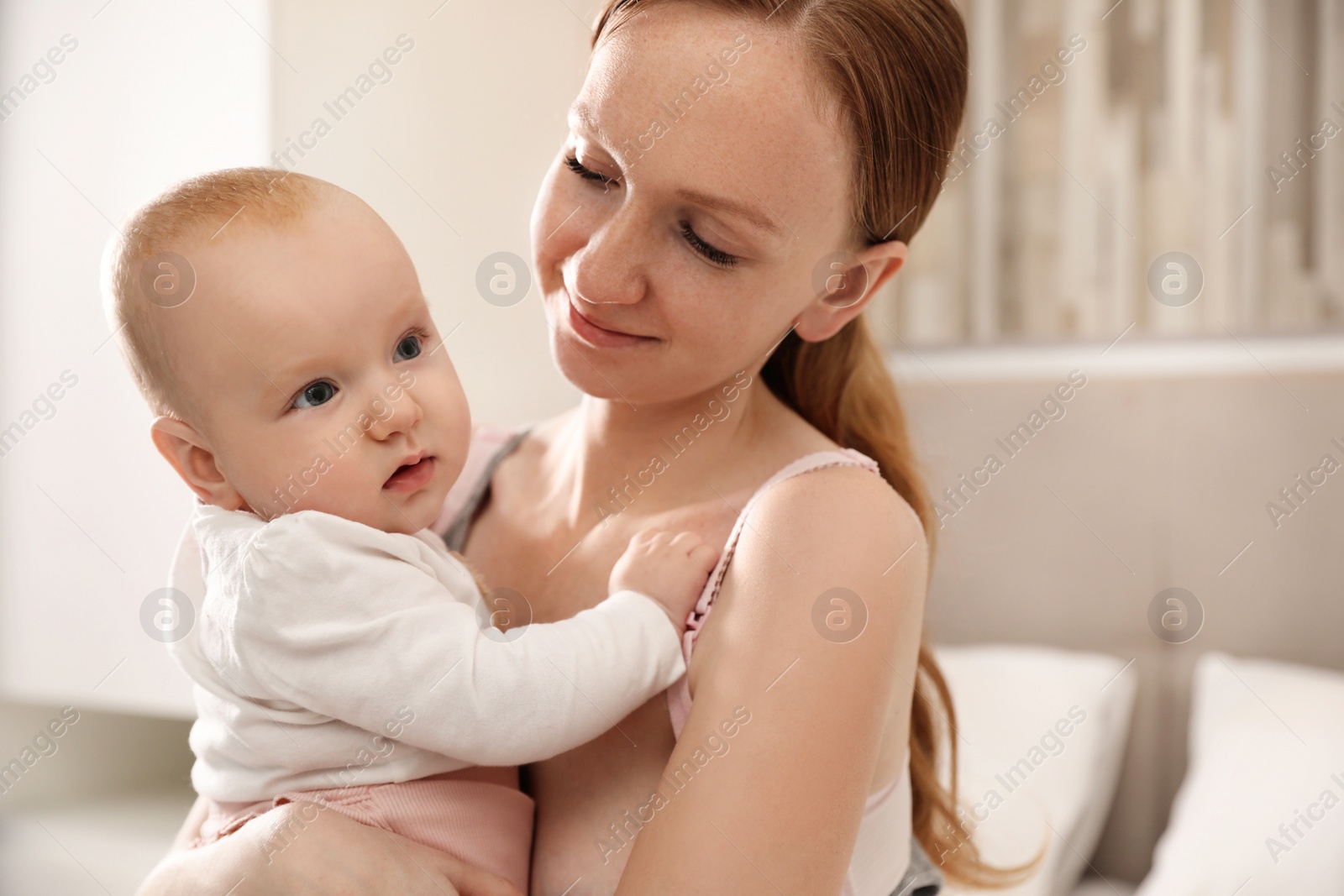 Photo of Young woman with her little baby resting after breast feeding in bedroom