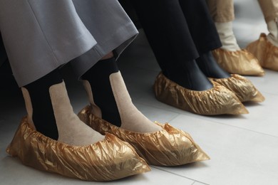 Women wearing shoe covers onto different footwear indoors, closeup