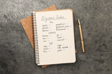 List with products of low, moderate and high glycemic index in notebook on grey table, flat lay