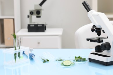 Photo of Food quality control. Microscope, petri dishes with different products and other laboratory equipment on light blue table