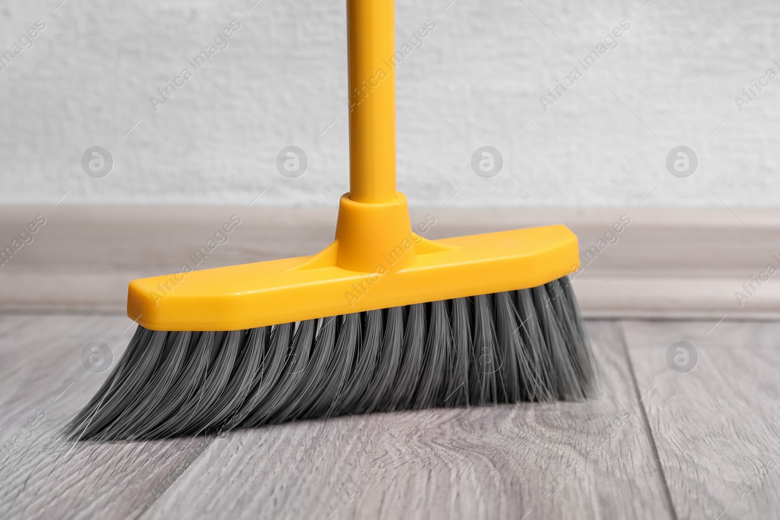 Photo of Sweeping wooden floor with plastic broom, closeup