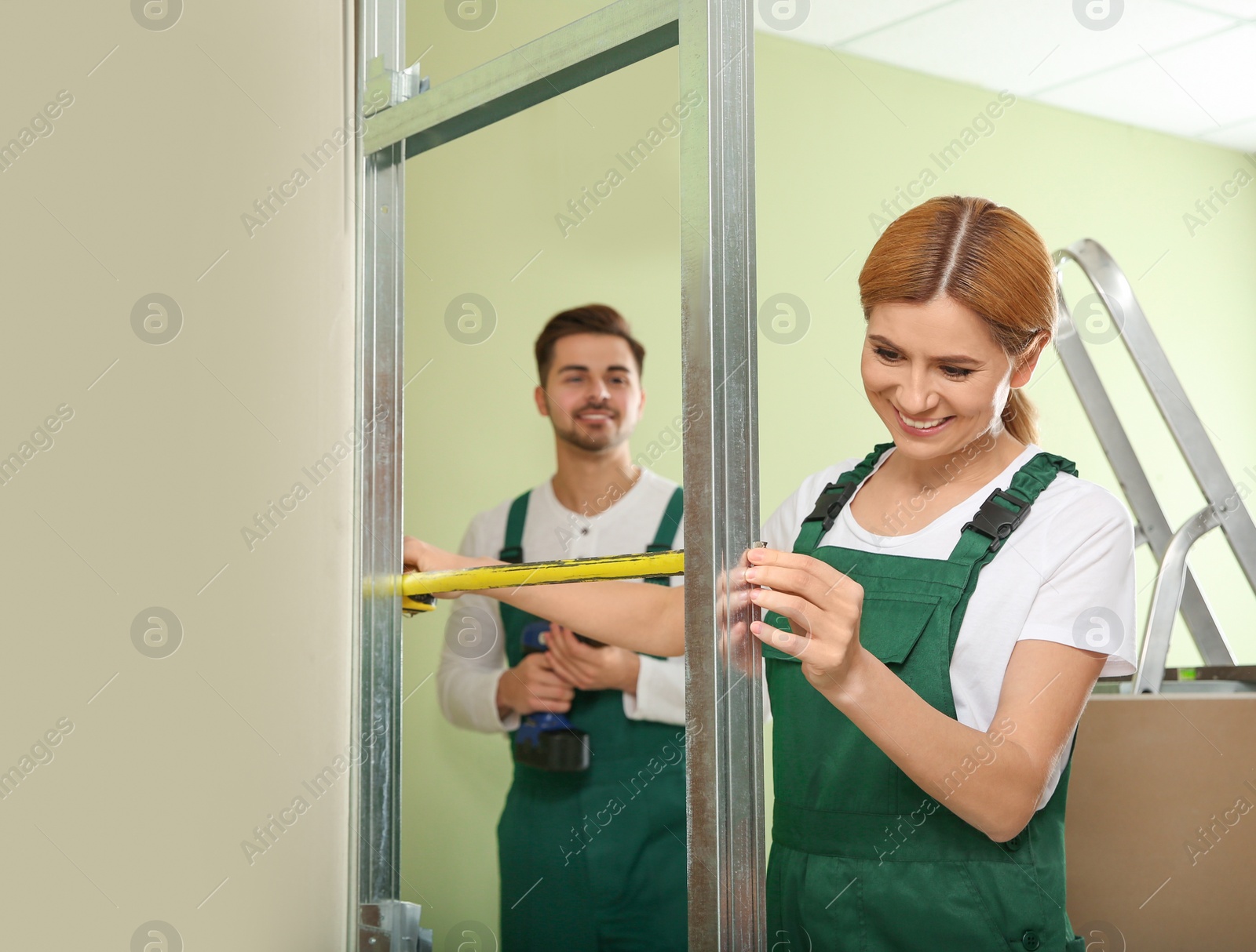 Photo of Workers installing drywall indoors. Home repair service