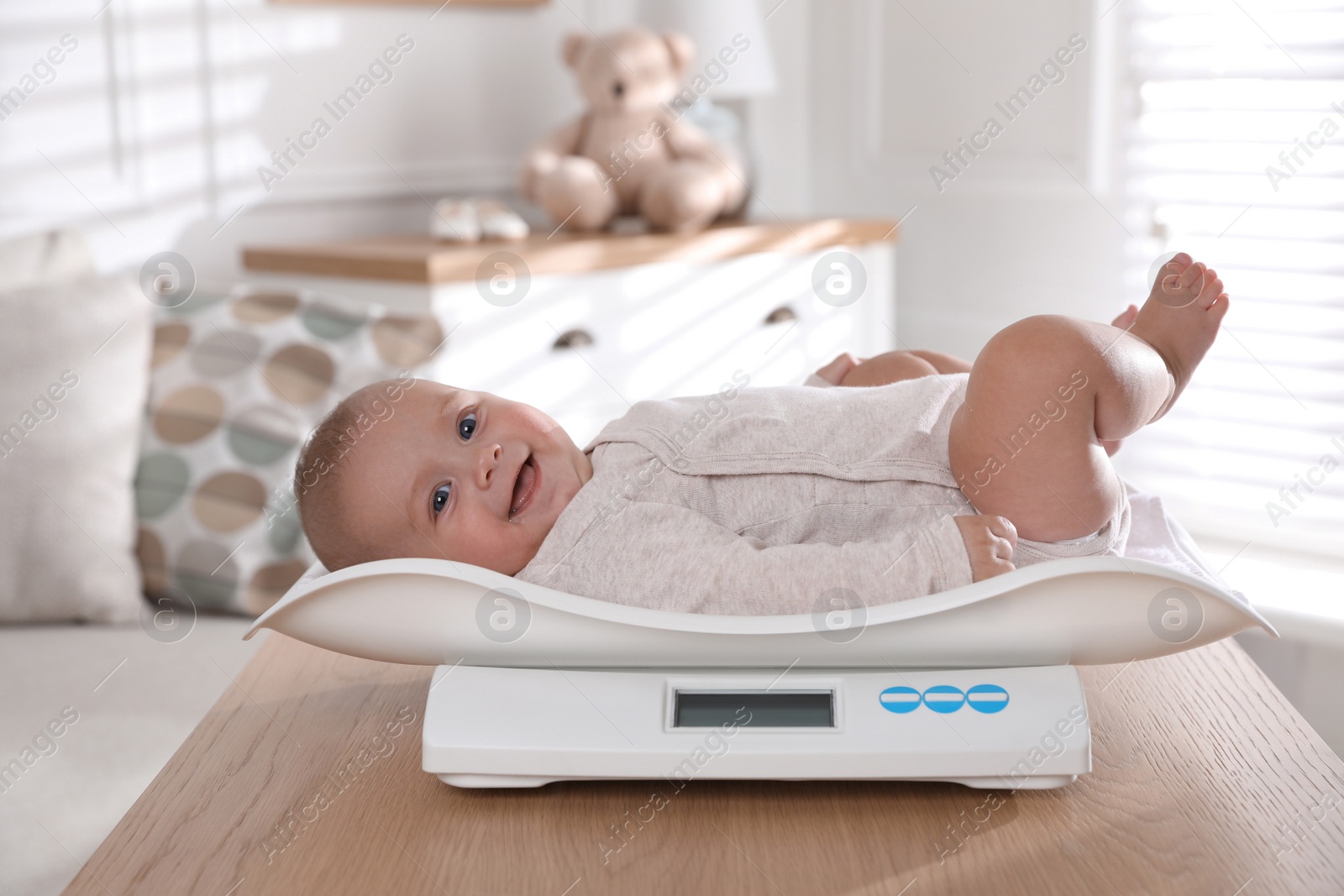 Photo of Cute little baby lying on scales at home