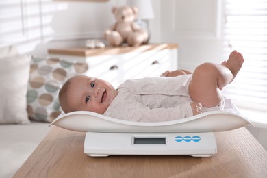 Cute little baby lying on scales at home