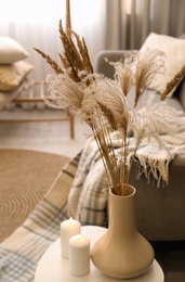 Dry plants and candles on table in room. Interior design