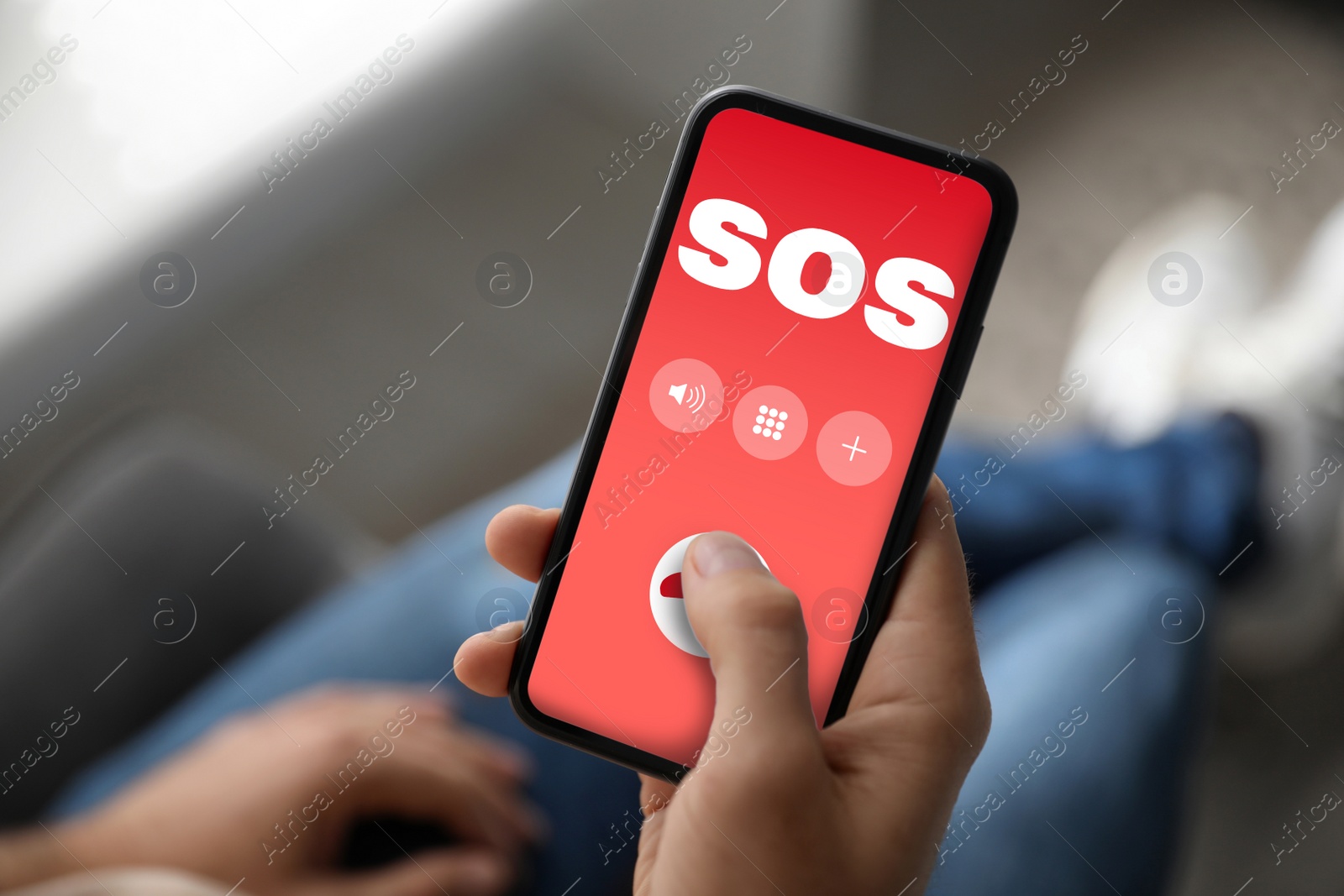 Image of Man holding smartphone with emergency call SOS on screen indoors, closeup