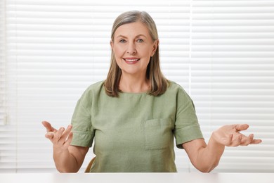 Happy woman at white table in room