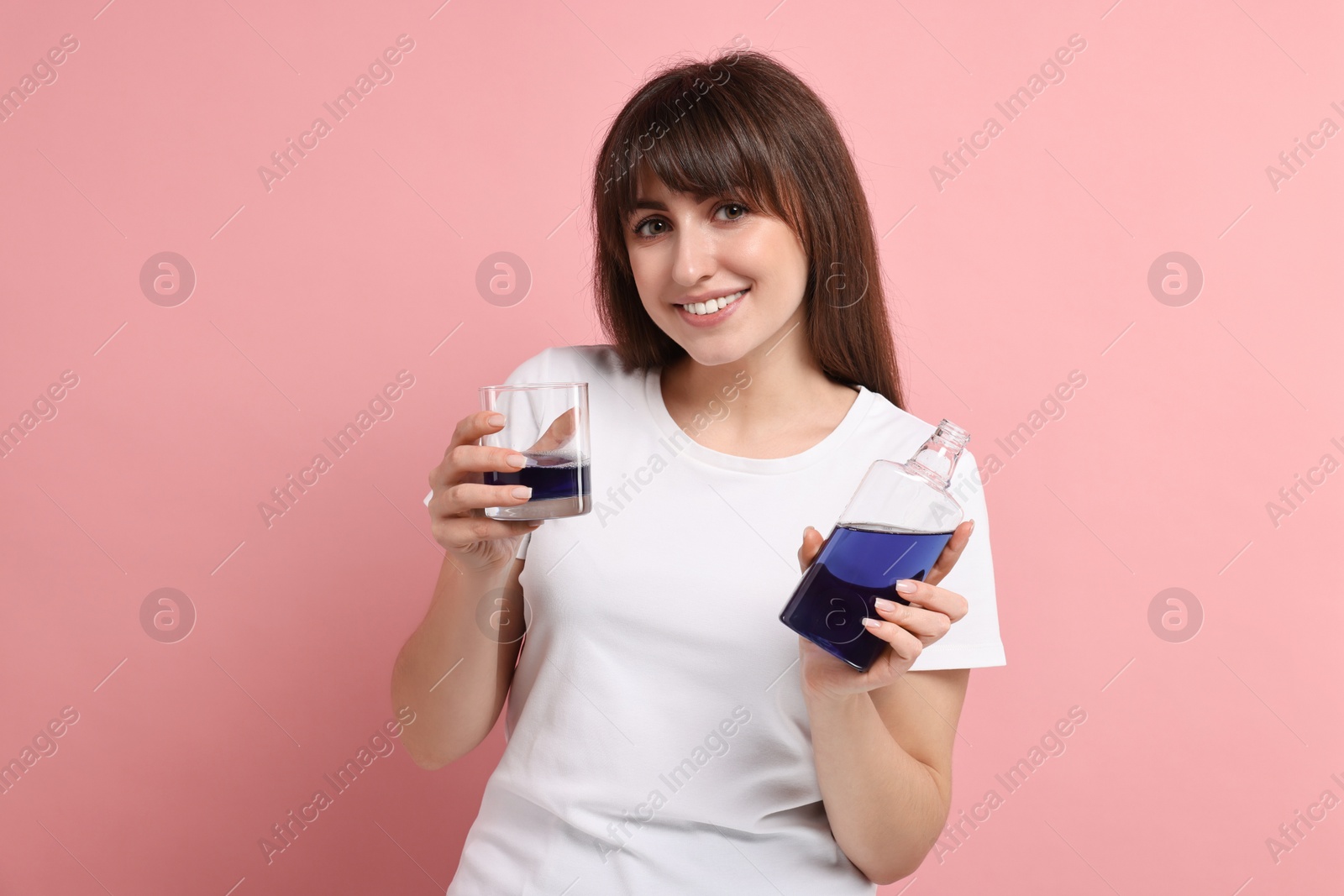 Photo of Young woman with mouthwash on pink background