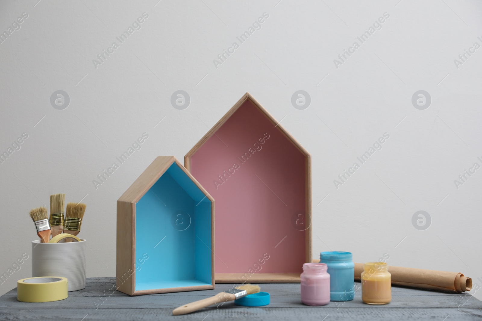 Photo of Brush with paint and wooden houses on grey table