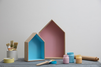 Brush with paint and wooden houses on grey table