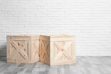 Photo of Wooden crates on floor at white brick wall. Space for text