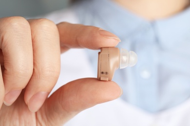 Photo of Doctor holding hearing aid, closeup. Medical device