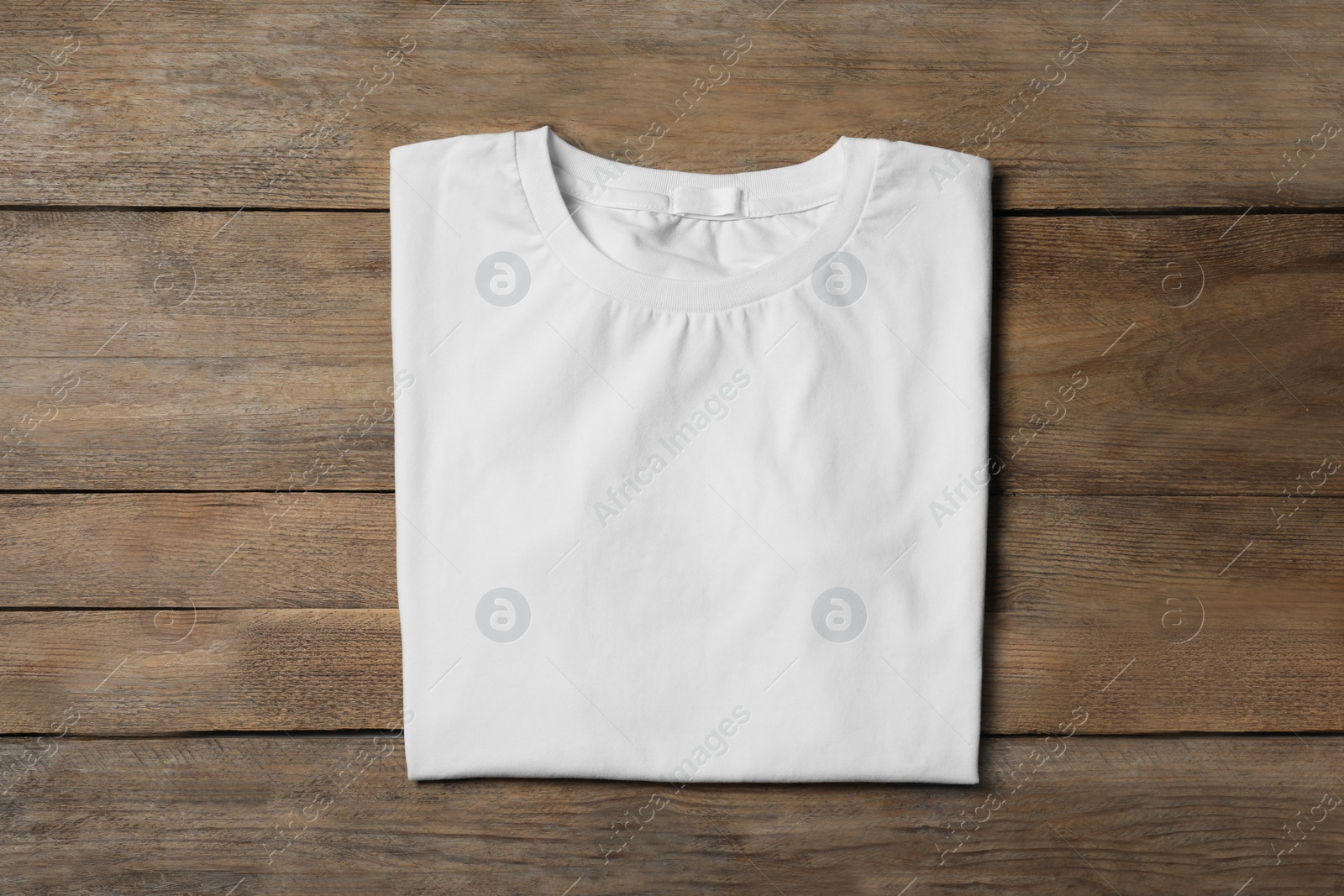 Photo of Stylish white T-shirt on wooden table, top view