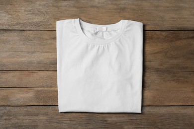 Photo of Stylish white T-shirt on wooden table, top view