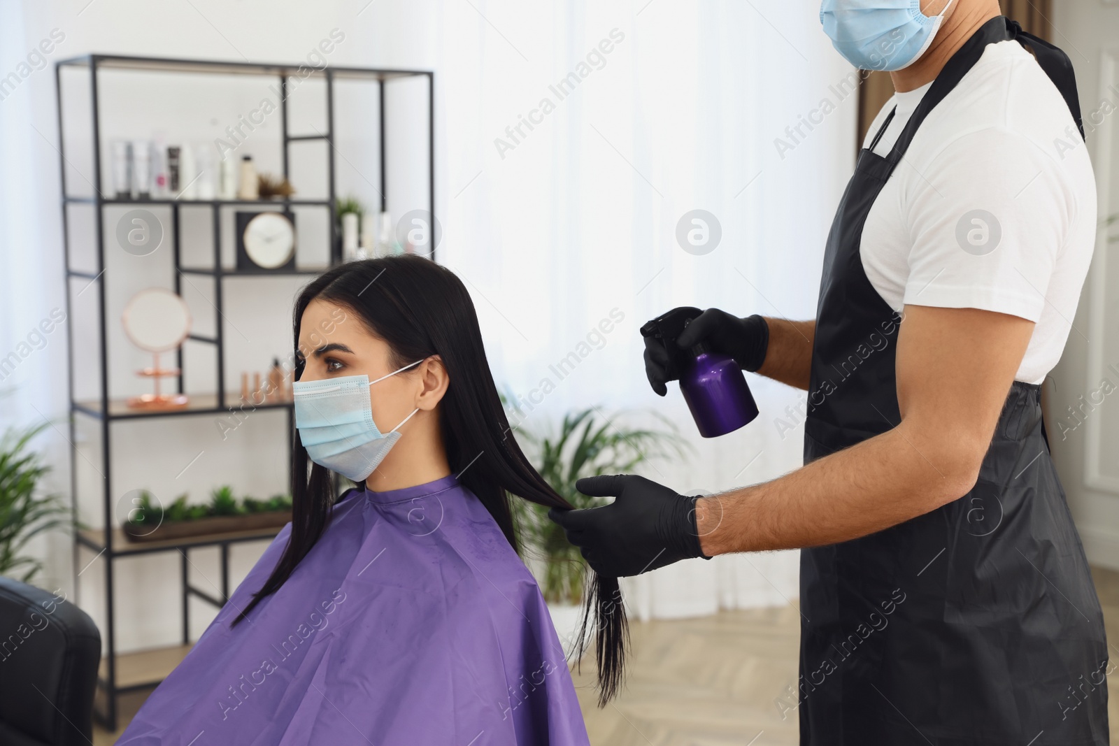 Photo of Professional stylist working with client in salon, closeup. Hairdressing services during Coronavirus quarantine