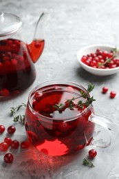 Photo of Delicious cranberry tea with thyme and berries on grey table