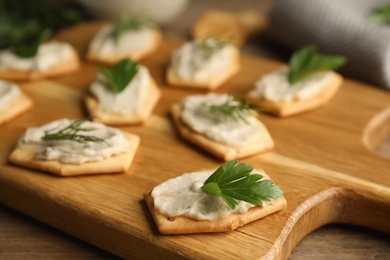 Photo of Delicious crackers with humus, parsley and dill on wooden table, closeup