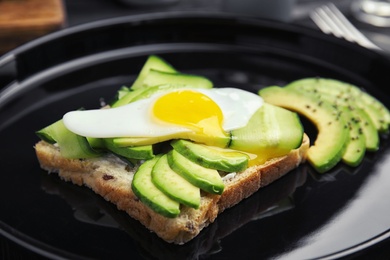 Photo of Crisp toast with avocado and quail egg on plate, closeup
