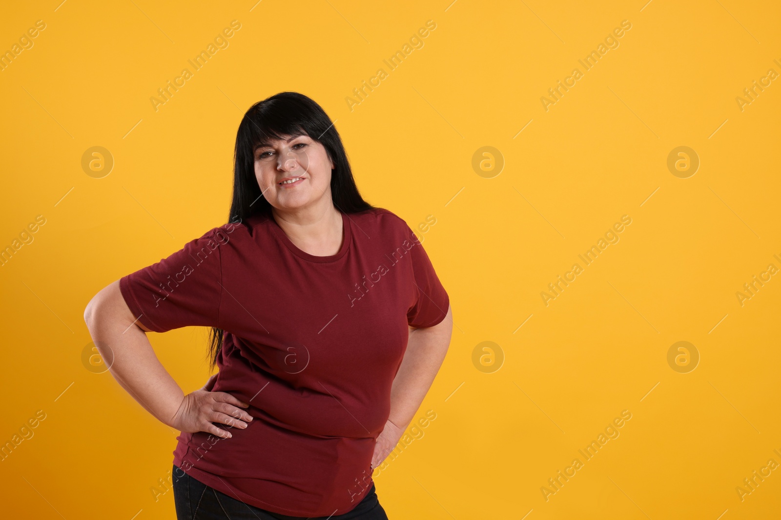 Photo of Beautiful overweight mature woman with charming smile on yellow background. Space for text