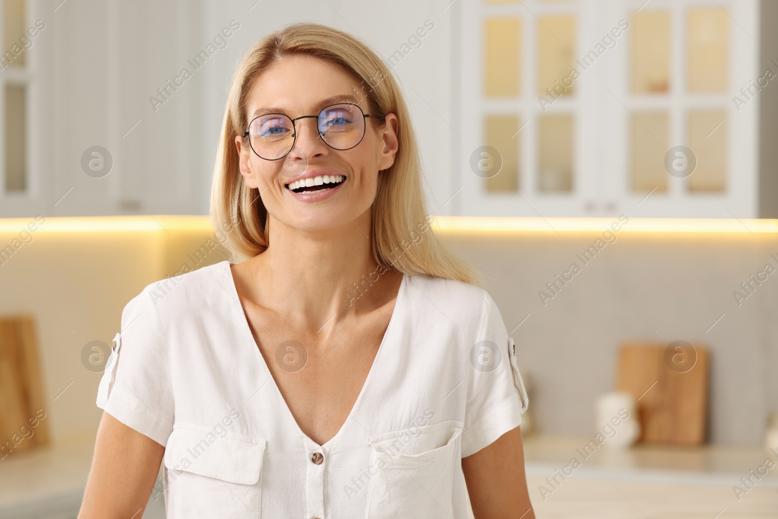 Photo of Portrait of smiling woman with stylish glasses in kitchen. Space for text