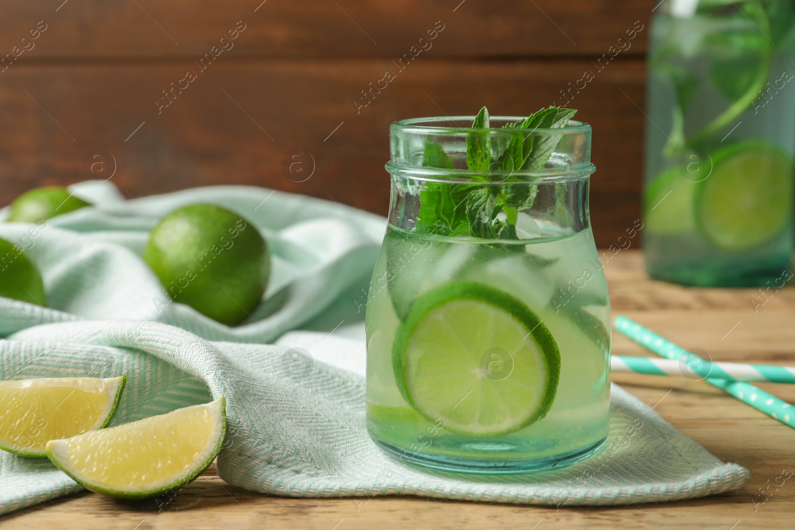 Photo of Natural lemonade with lime in jar on wooden table