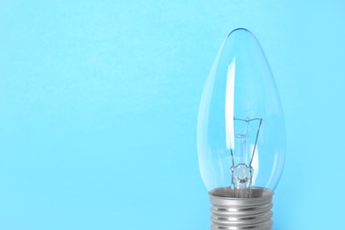 New modern lamp bulb on light blue background, space for text