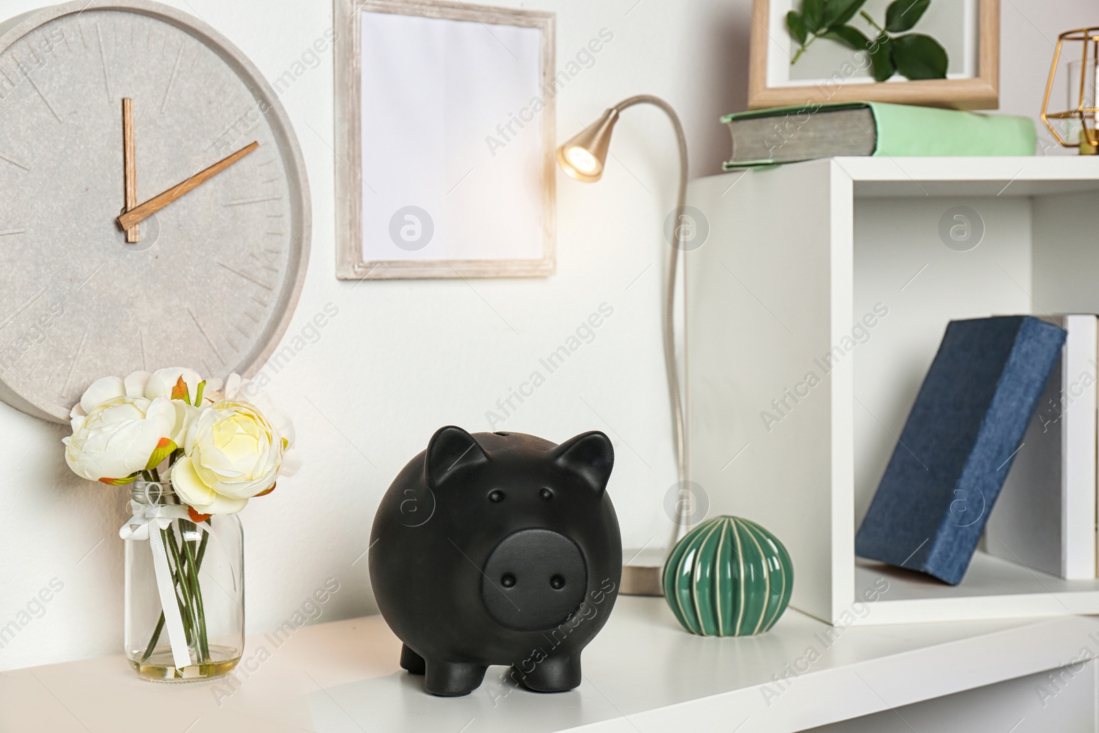 Photo of Cute piggy bank on shelf indoors. Stylish interior element