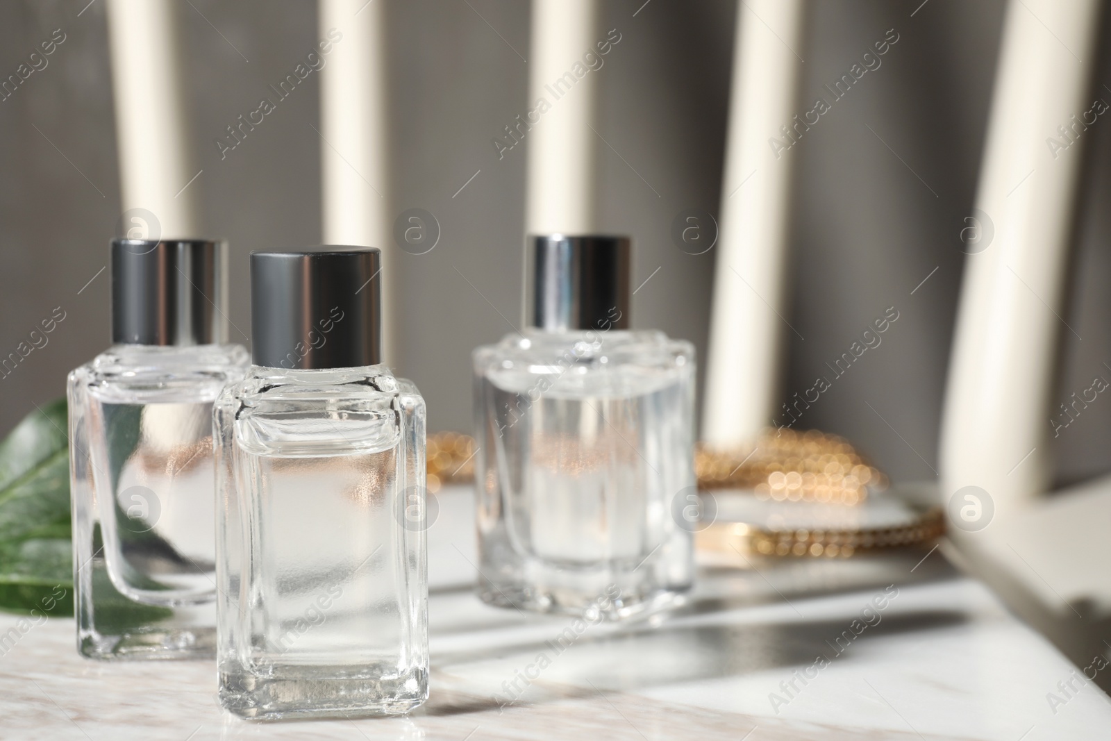 Photo of Bottles of essential oil on white marble table, space for text