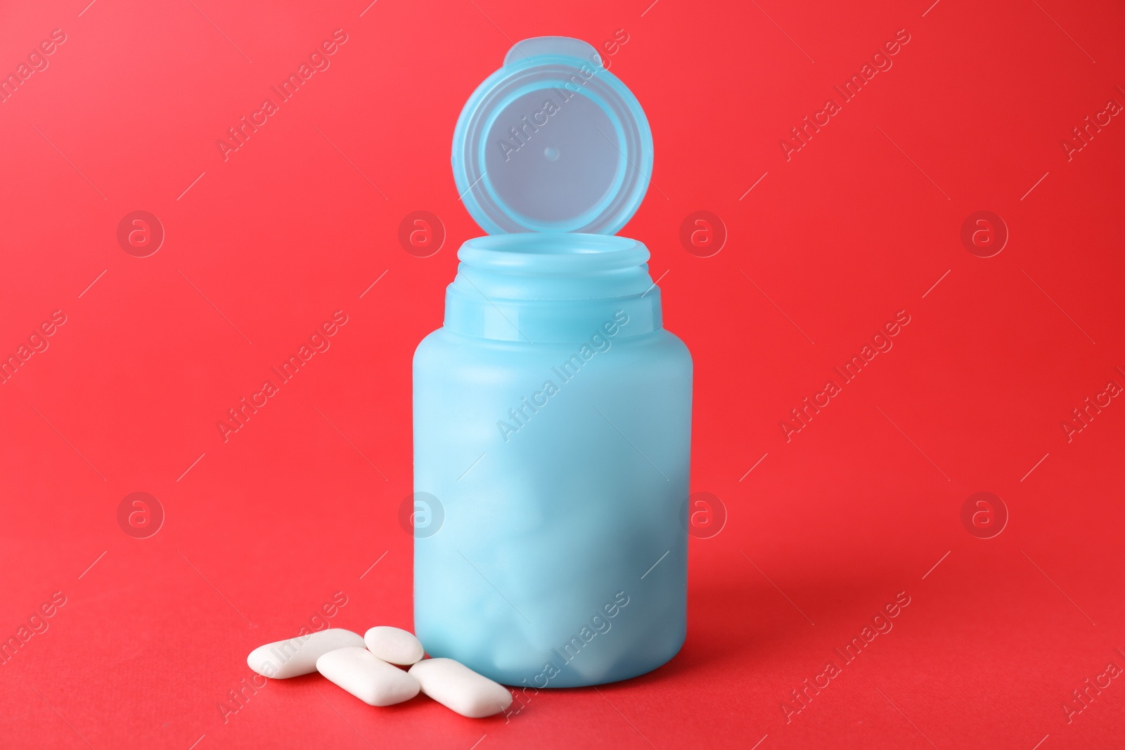 Photo of Jar with chewing gums on red background