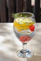Delicious refreshing lemonade with raspberries on beige table outdoors