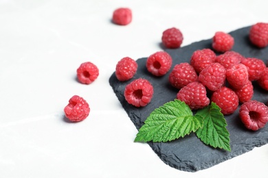 Slate plate with ripe aromatic raspberries on table, closeup