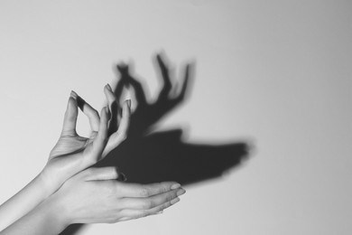 Photo of Shadow puppet. Woman making hand gesture like deer on light background, closeup with space for text. Black and white effect