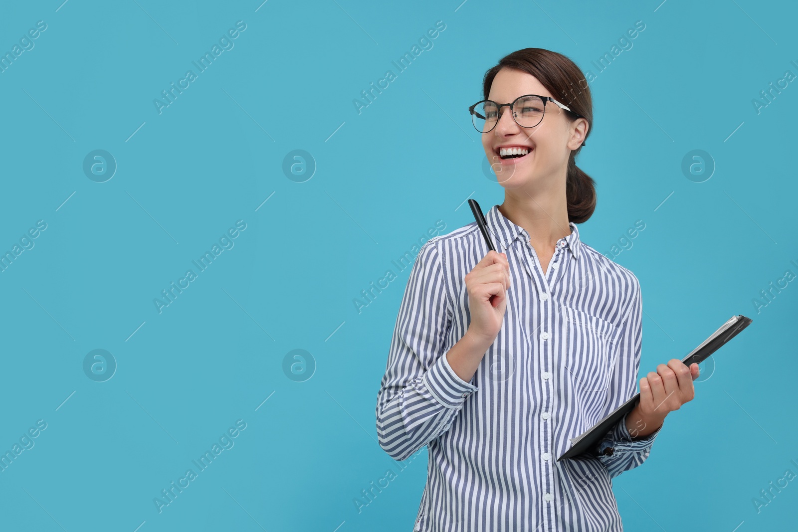 Photo of Happy secretary with clipboard and pen on light blue background, space for text