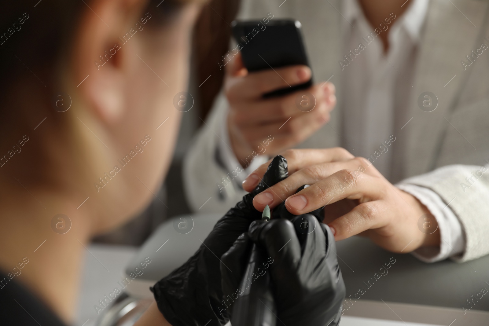 Photo of Professional manicurist working with client in beauty salon, closeup