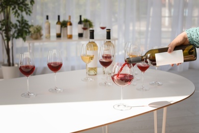 Woman pouring wine into glass on table