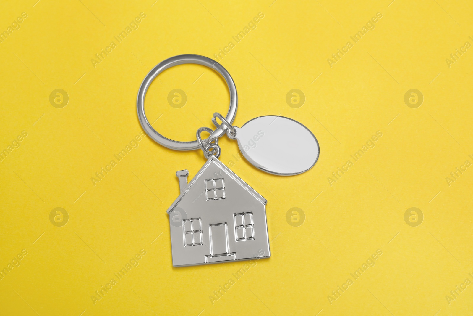 Photo of Metal keychains with silver key ring on yellow background, top view