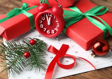 Composition with calendar, alarm clock and gifts on wooden background, closeup. Boxing Day