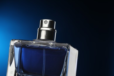 Luxury men`s perfume in bottle against dark blue background, closeup. Space for text