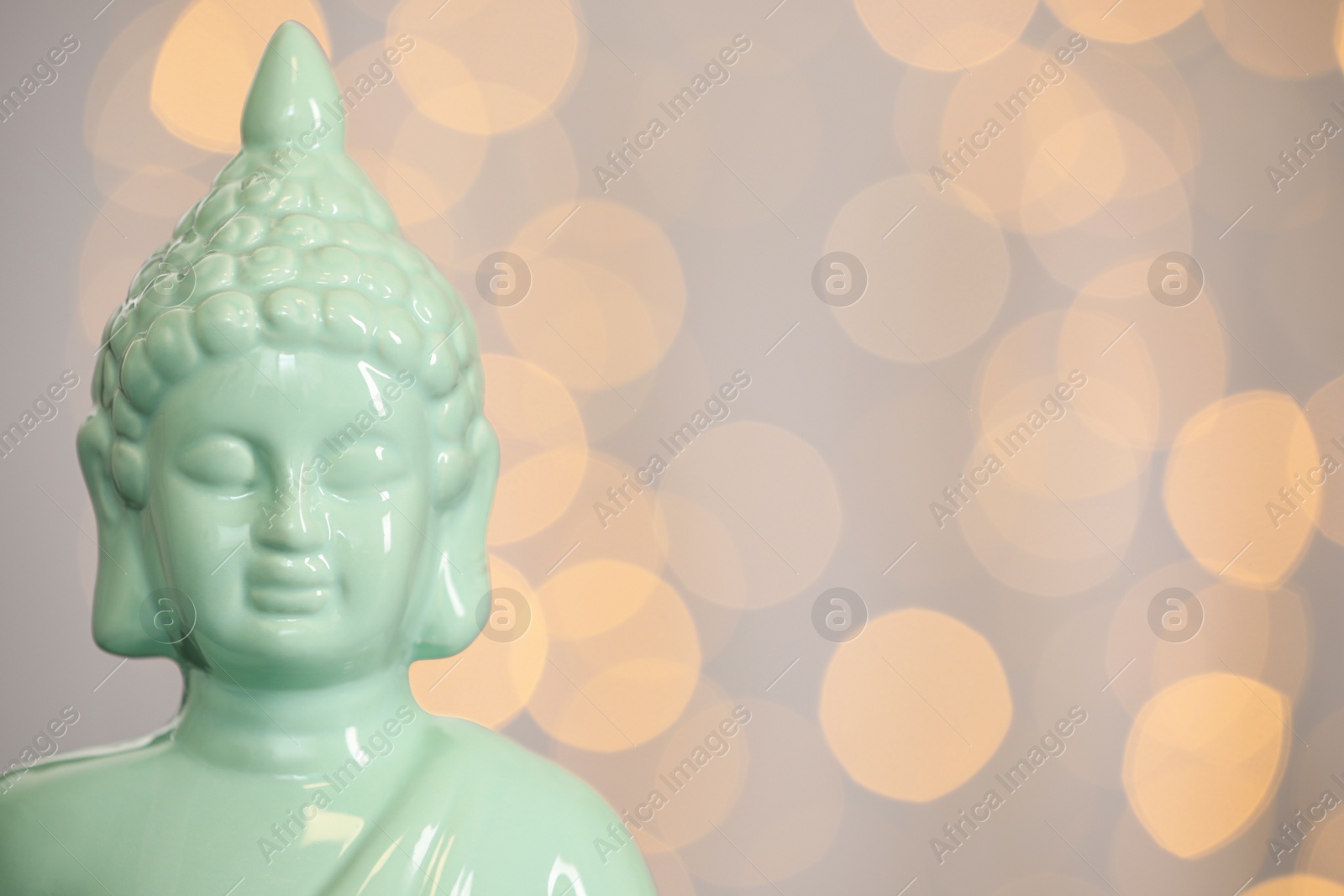 Photo of Buddha statue against blurred lights, closeup. Space for text