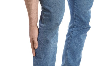 Young man suffering from leg pain on white background, closeup