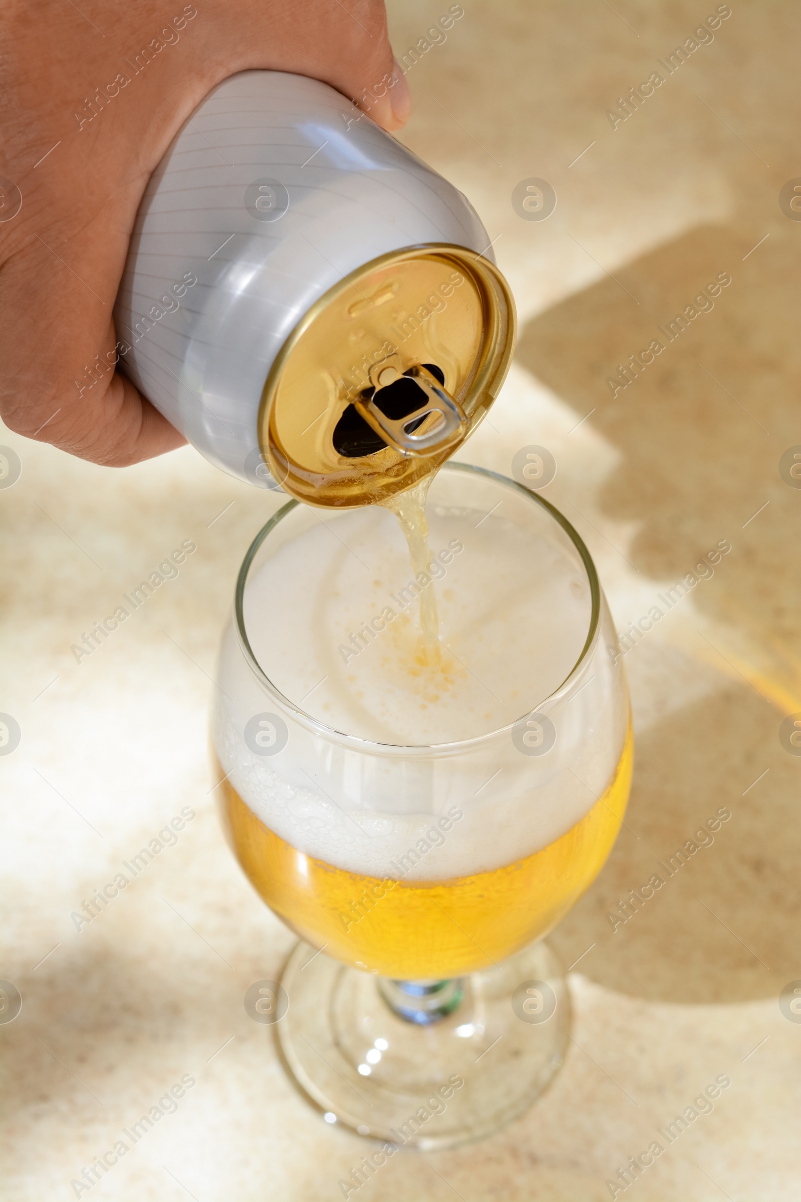 Photo of Man pouring beer from can into glass at table, closeup