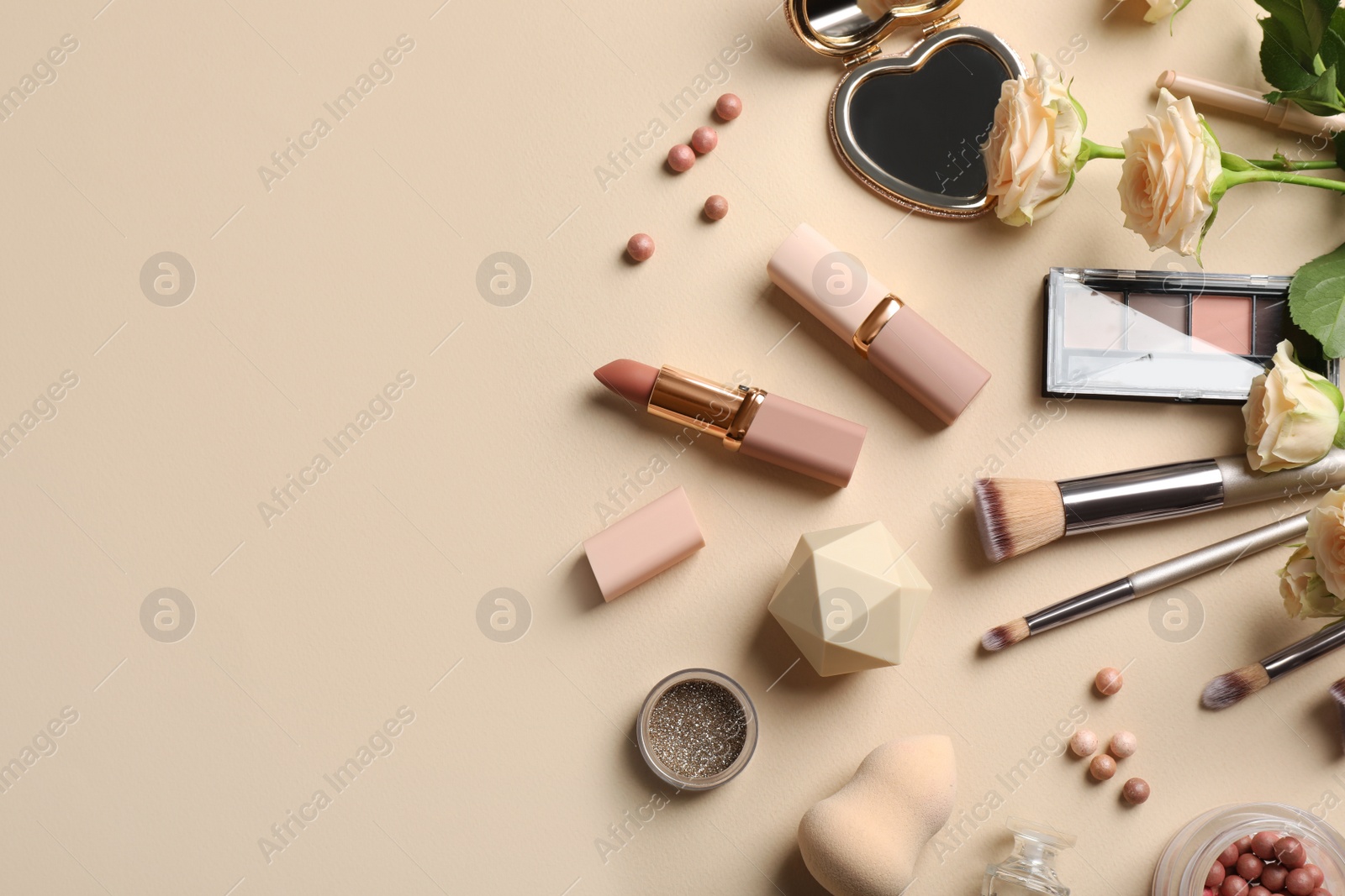 Photo of Flat lay composition with makeup products and beautiful roses on beige background, space for text