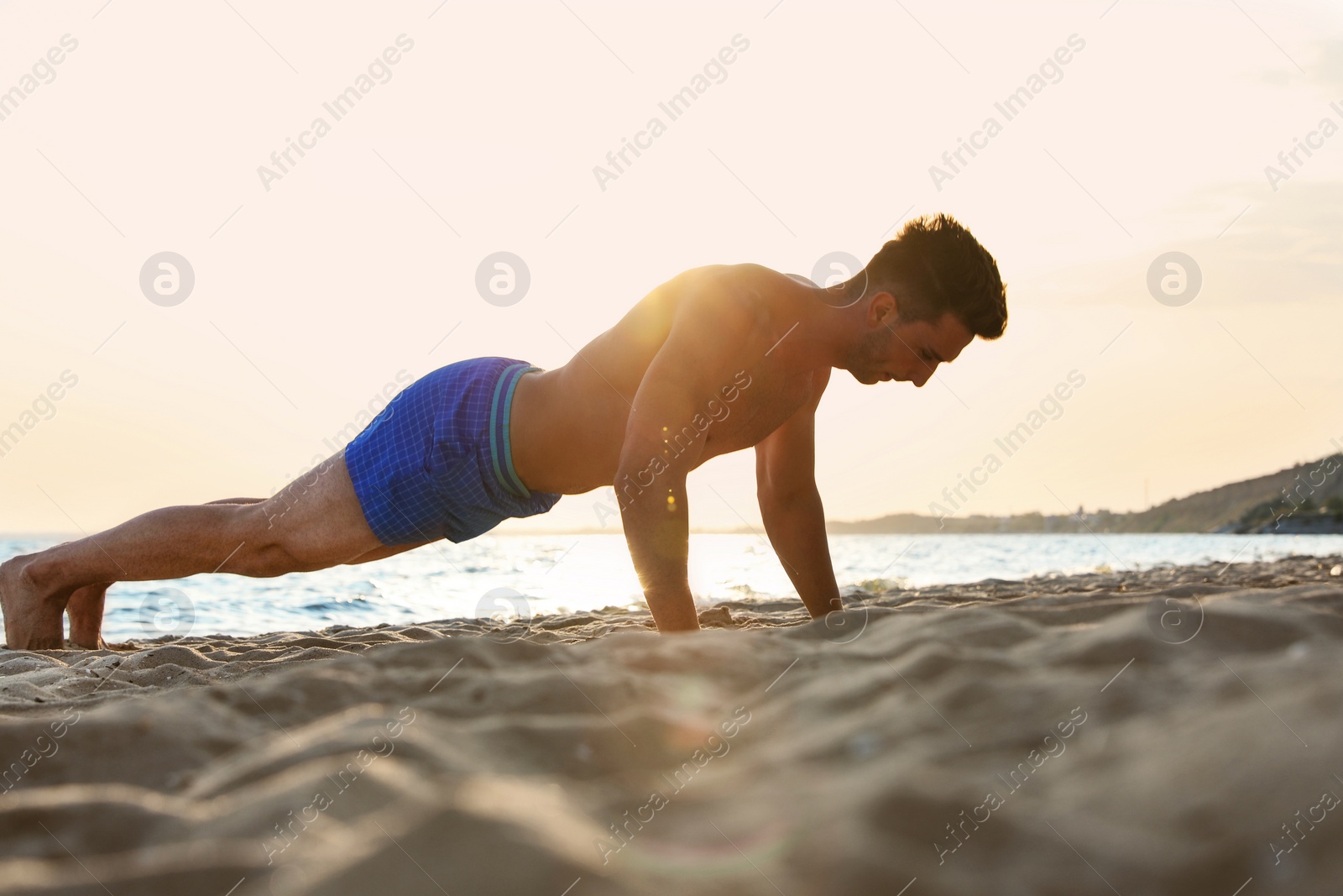 Photo of Young man doing push ups on beach