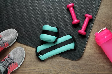 Photo of Turquoise weighting agents and sport equipment on wooden table, flat lay