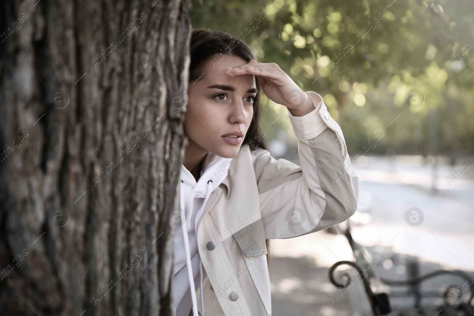 Image of Young woman spying on her boyfriend in park. Cheating concept