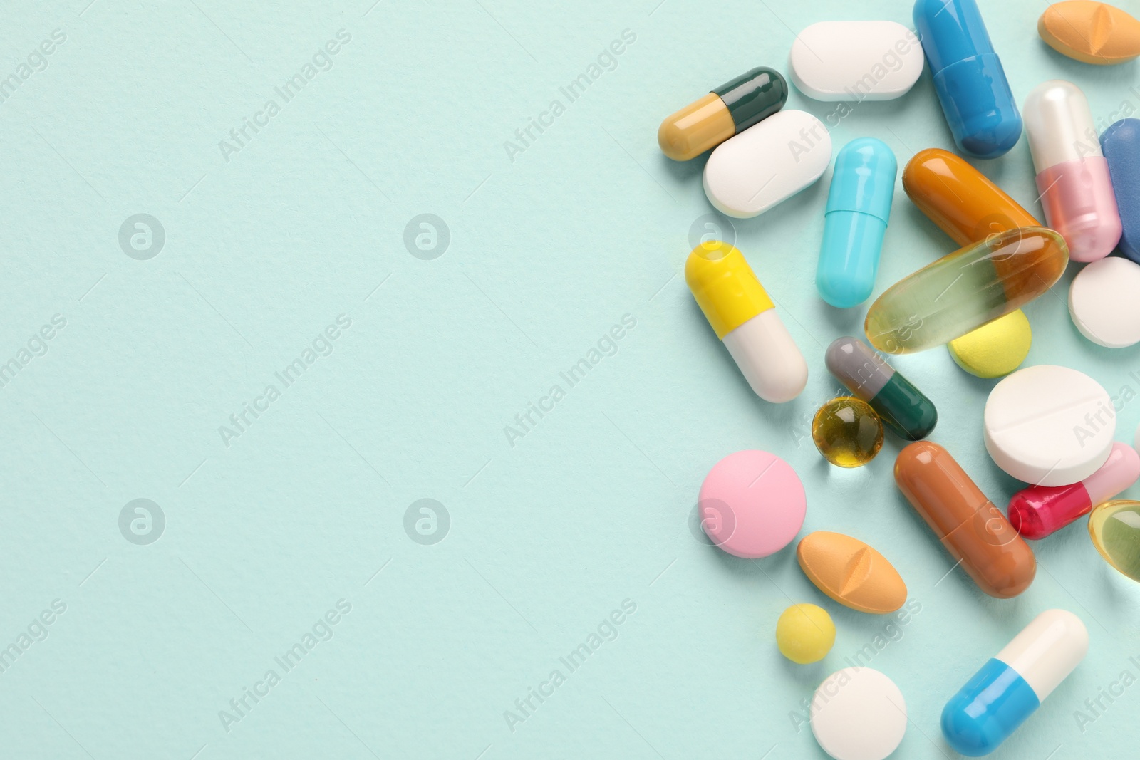 Photo of Pile of different pills on mint background, flat lay. Space for text